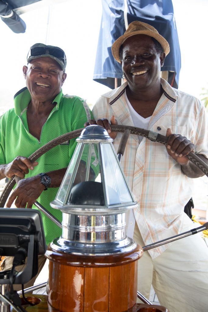 The Varnish Doctors standing behind the wheel of a classic yacht with beautiful varnish
